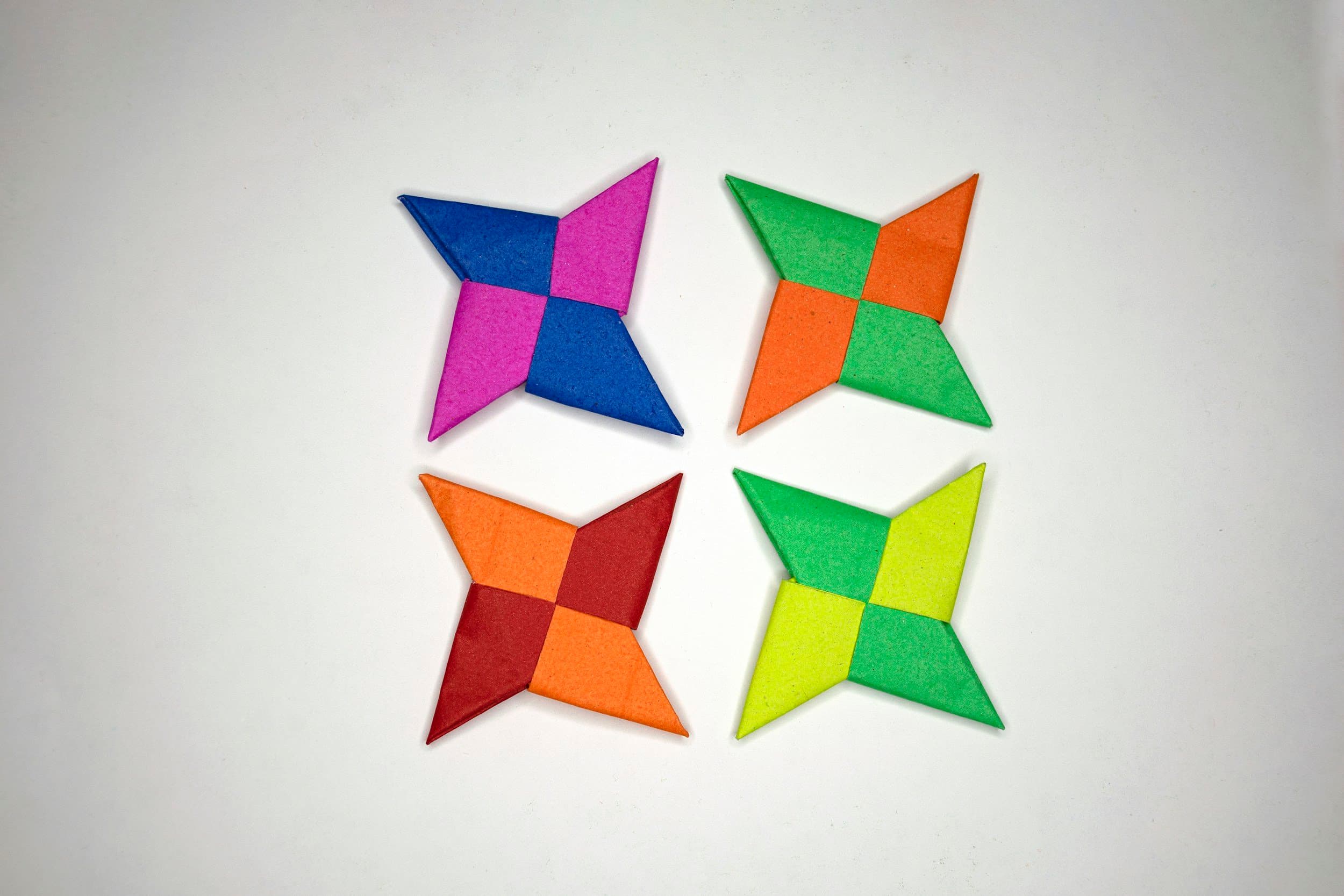 Four colorful star-shaped quilt blocks arranged on a white surface, each with different bright colors and patterns.